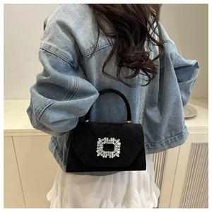 Detail of elegant black suede bag featuring a square rhinestone buckle and chain strap
