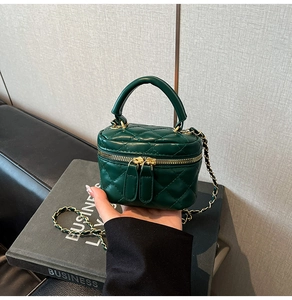 Macro detail of dark green quilted leather vanity bag with gold chain and handle