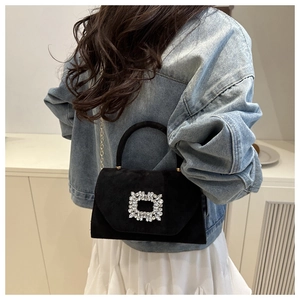 Modèle portant un sac bandoulière en daim noir avec boucle strass et chaîne dorée