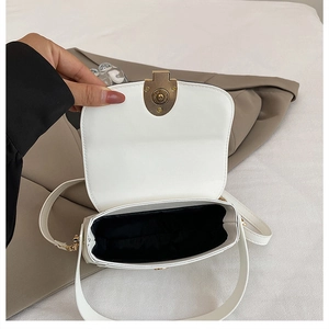 Détail du sac bandoulière blanc montrant le fermoir doré et la doublure intérieure noire