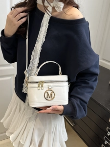 Borsa a mano bianca con logo M dorato indossata da una modella in stile minimal
