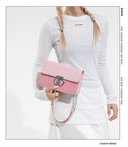 Detail of pink woven leather chain bag with silver circular clasp on white silk skirt