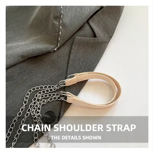 Detail of silver metal chain strap with beige leather stitching for a small square bag