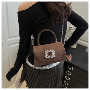 Détail d'un sac en daim marron avec boucle en cristal carrée et bandoulière chaîne dorée