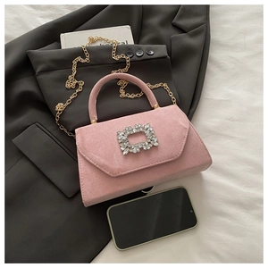 Close-up of pink suede handbag with square rhinestone buckle and golden chain strap