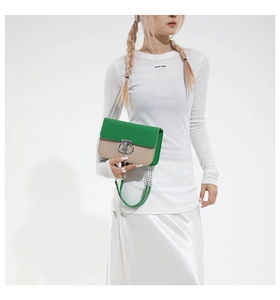 Detail of green leather and straw crossbody bag with silver lock and chain strap