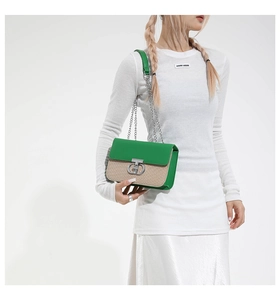 Close-up of green leather and straw woven bag featuring a silver metal ring lock