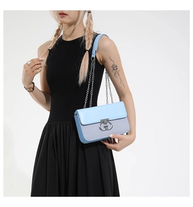 Detail of light blue shoulder bag with woven texture and silver metal twist lock
