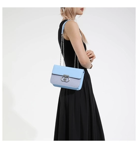 Close-up of light blue handbag featuring dual-texture leather and silver chain strap