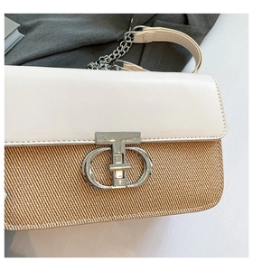 Detail of elegant shoulder bag featuring woven texture and silver metal brand buckle