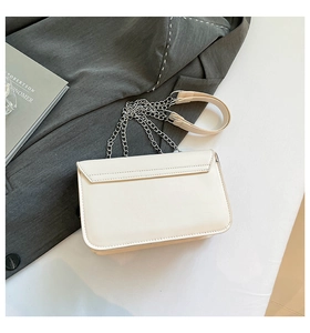 Detailed close-up of cream leather shoulder bag with silver chain strap and metal lock