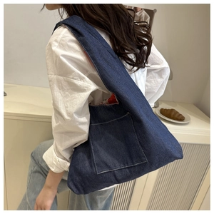 Détail du grand sac cabas en denim bleu avec doublure florale rouge et poche avant apparente