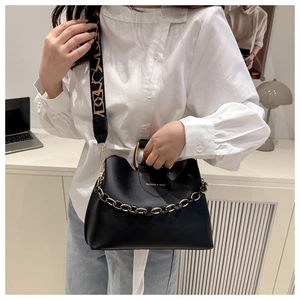 Detail of black leather bucket bag with chunky gold chain and patterned wide shoulder strap