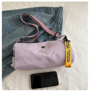 Détail du sac baril en nylon lilas avec un ruban décoratif jaune sur la fermeture