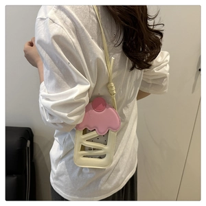 Detail of cute cupcake-shaped pink crossbody bag worn by a model in casual style
