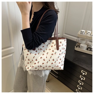 Vue détaillée du sac cabas blanc avec motif cerise et lanières brunes sur un mannequin
