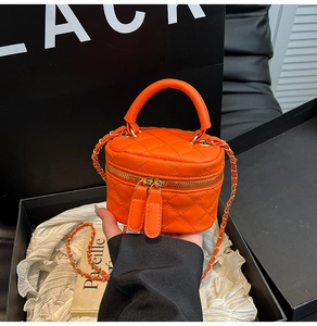 Detail of orange quilted mini square bag with gold chain strap and dual zipper closure