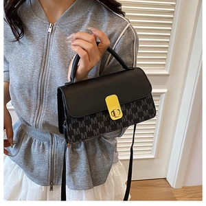 Detailed view of the small square bag with M-letter texture and golden metal rotary lock