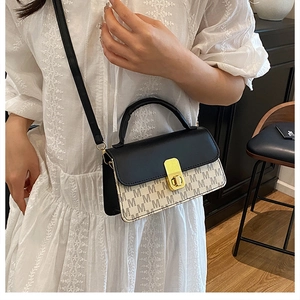 Close-up of a two-tone leather crossbody bag with M-pattern texture and gold twist lock
