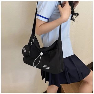 Detail of black nylon crossbody bag with drawstring design and mini coin purse attachment