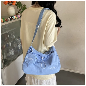 Back view of light blue nylon crossbody bag with drawstring and small coin purse charm