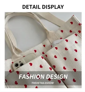 Detail of corduroy tote bag showing front pockets holding a smartphone and earbuds