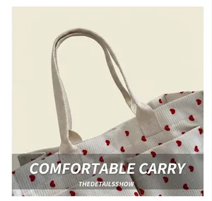Detail of white corduroy tote bag with red heart pattern and reinforced handles