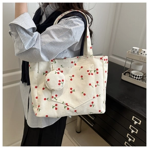 Detail of white corduroy tote bag featuring red cherry prints and matching coin purse