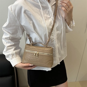 Elegant khaki box bag with textured finish shown on shoulder in a stylish urban setting