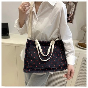 Detail view of navy blue corduroy tote bag featuring red heart patterns and adjustable strap