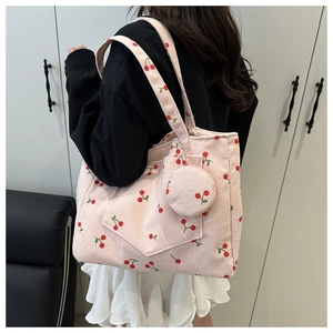 Pink corduroy tote bag with cherry print and matching pendant shown on shoulder