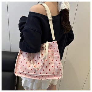 Detailed view of pink corduroy tote bag with red heart embroidery and cream canvas straps