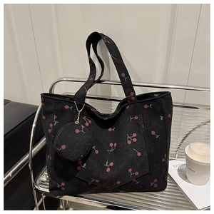 Détail du sac cabas en velours côtelé noir avec broderie cerise et petit porte-monnaie assorti