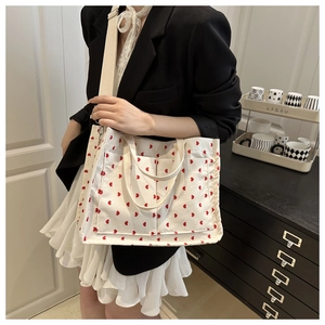 Detail of corduroy tote bag with red heart pattern and wide shoulder strap on a model