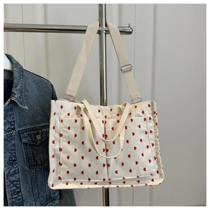 Detail of off-white corduroy tote bag with red heart patterns and double front pockets