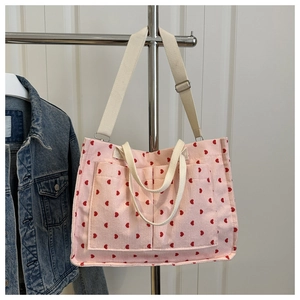 Detail of pink corduroy tote bag with red heart pattern showing large front pockets
