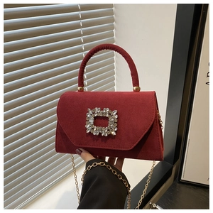 Detail of burgundy suede-style handbag featuring a sparkling rhinestone buckle and gold chain