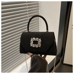 Detailed macro view of the black suede texture and sparkling crystal square buckle on the bag