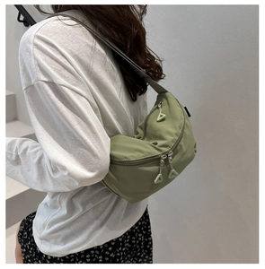 Sage green crescent nylon crossbody bag showing the back view and strap length on a model