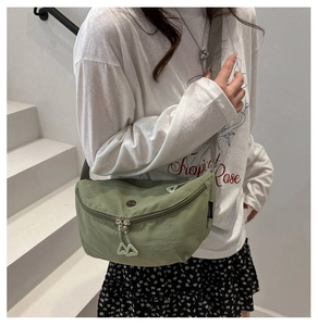 Close-up of light green nylon crescent bag featuring FANYISSA brand tag and dual zippers