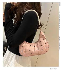 Détail du sac hobo rose avec broderie de nœuds et bandoulière en perles élégantes