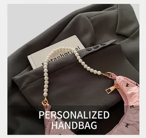 Détails d'un sac à main plissé rose avec poignées en perles sur un blazer élégant