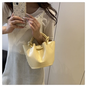 Détail du sac seau plissé jaune clair en cuir verni avec une poignée à anneau noué