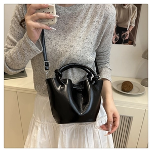 Détail du sac seau plissé noir avec poignée tissée ronde et gaufrage de mode