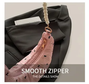 Détail du sac plissé rose montrant le zip métallique lisse et le décor de perles