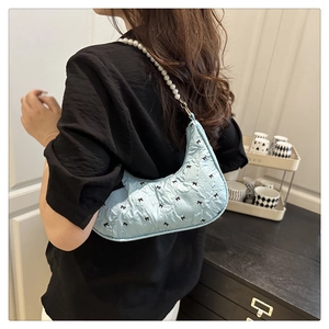 Vue détaillée d'un sac hobo bleu à nœuds papillon avec une anse élégante en perles