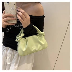 Detail of light green ruched handbag with twisted handle shown in a mirror selfie