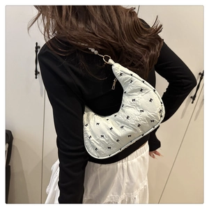 Détail du sac sous le bras à nœud papillon avec perles blanches et anneaux dorés