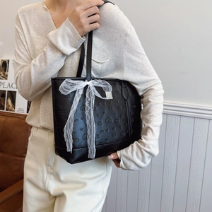 Sac fourre-tout noir gaufré à nœud en dentelle blanche porté par un mannequin
