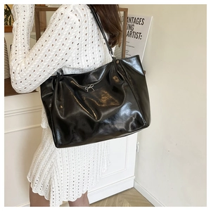 Detail of black glossy tote bag with silver bow accent and spacious interior for daily use